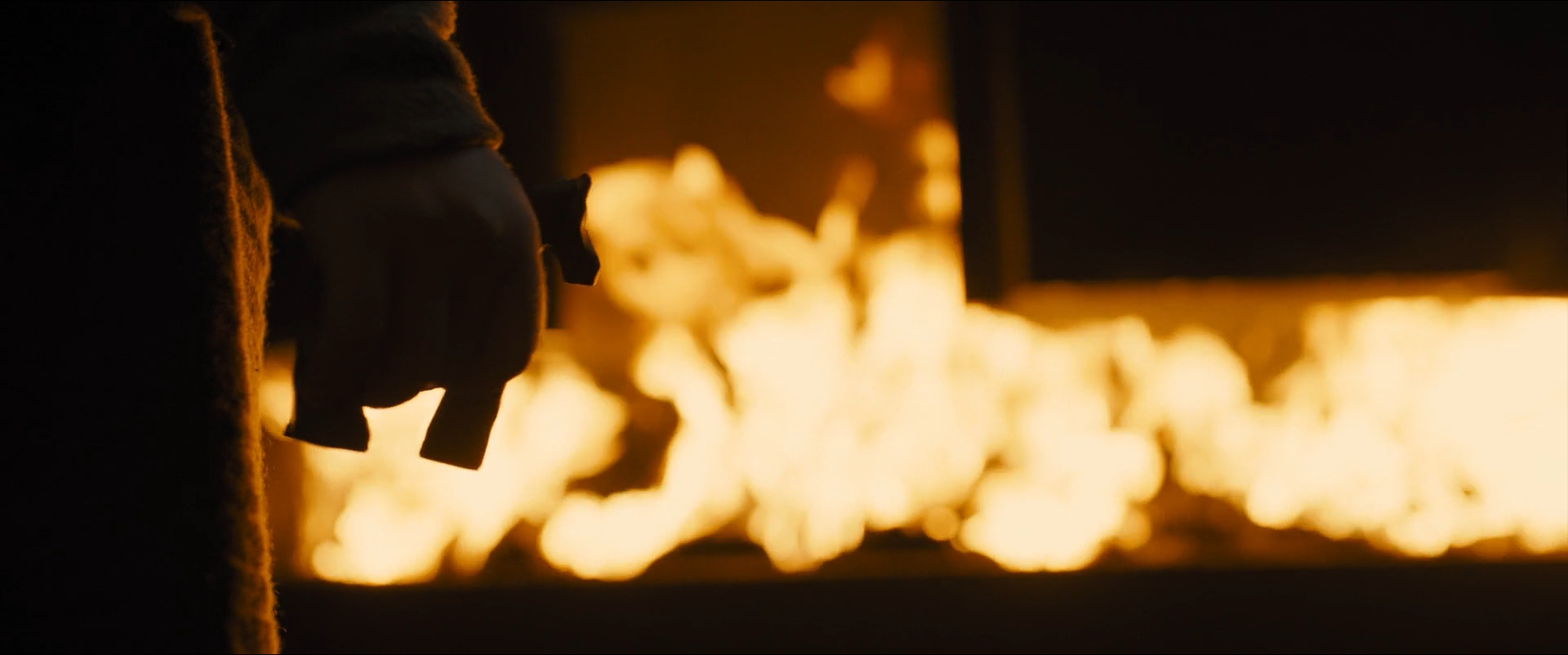 Shot 0516 from Blade Runner 2049 at 01:52:33:05. The furnace mouth burns out to white across the centre while the coat and glove in front of it retain no detail at all, leaving an image built from essentially two values.