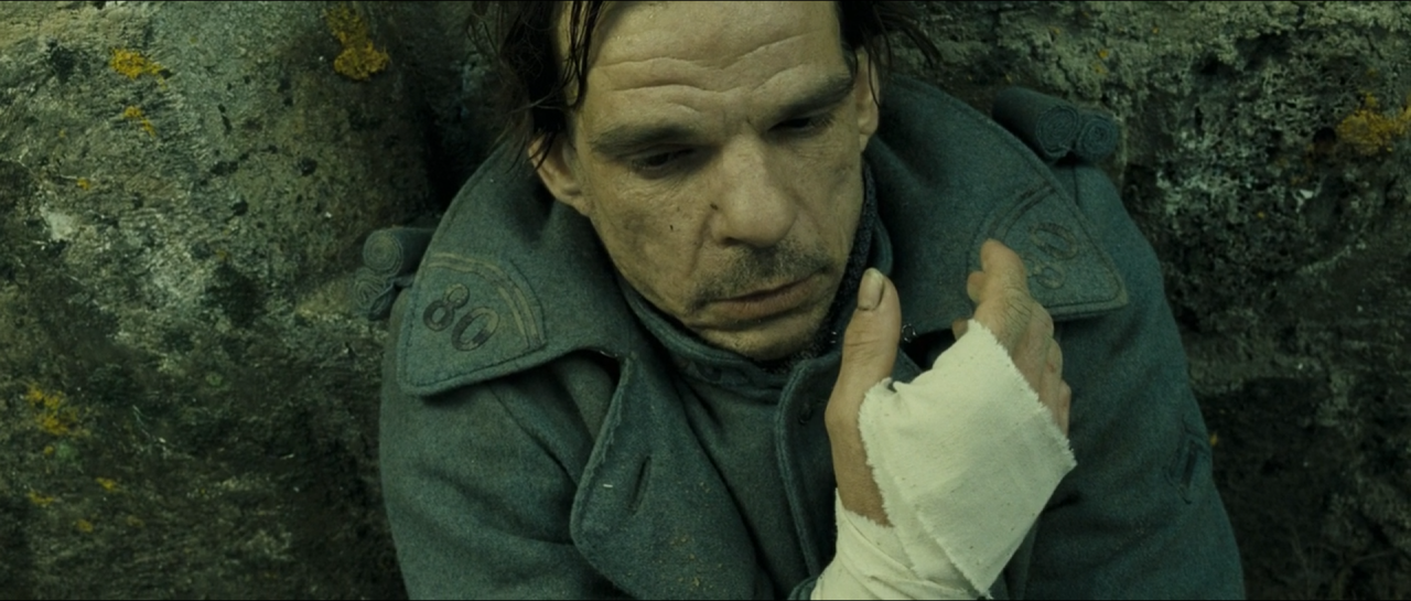 A wounded soldier outdoors in muted cyan-grey uniform and light.