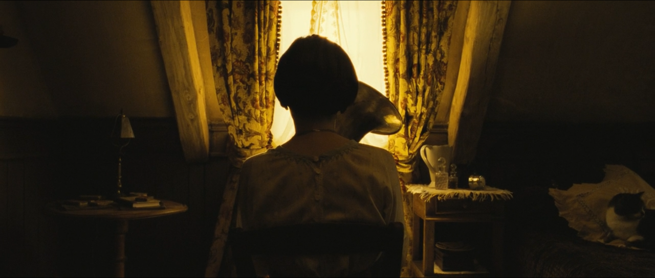 A seated reader silhouetted against softly glowing patterned golden curtains.