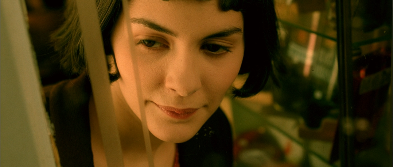 Close-up of Amélie against an olive-green background in warm light.