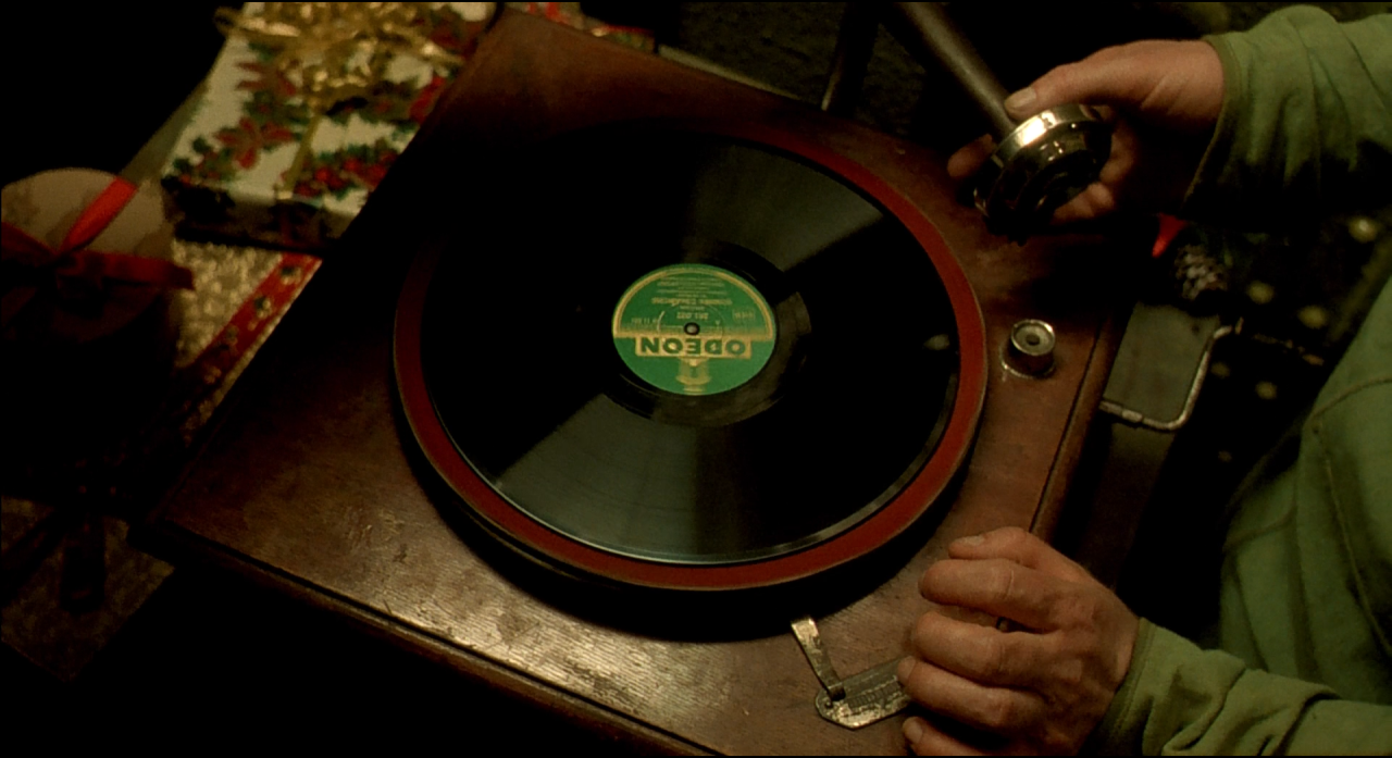 A record player and small coloured objects emerging from deep black shadows.